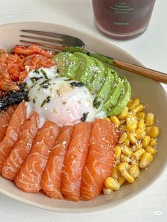 a white plate topped with different types of food next to a fork and glass of water