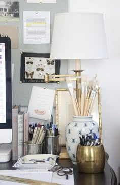 a desk with a computer, pen holder and other office supplies on top of it