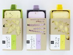 three boxes with different types of soaps in them on a white surface, one is yellow and the other is green