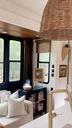 a living room filled with furniture and windows next to a kitchen counter top under a light fixture