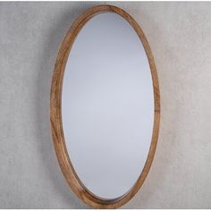 an oval wooden mirror mounted on the wall