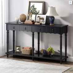 a black console table with two drawers and pictures on it next to a white rug