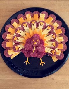 a black plate topped with cheese and meats next to a turkey shaped platter