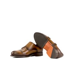 a pair of brown leather shoes with an orange stripe on the bottom and black soles