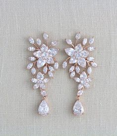 two pairs of earrings with white stones on the bottom and one has a flower design