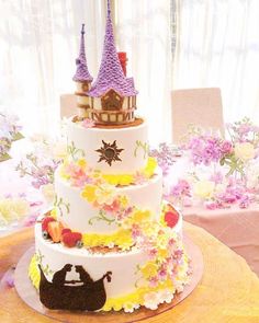 a three tiered cake decorated with flowers and castle