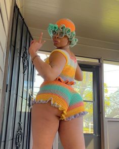 a woman in a colorful crocheted bathing suit standing next to a metal gate