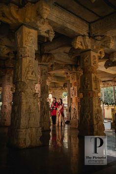 two people are standing in the middle of some pillars