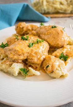 a white plate topped with meat covered in gravy and garnished with parsley