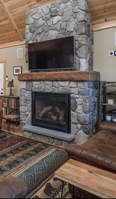 a living room with a stone fireplace and flat screen tv