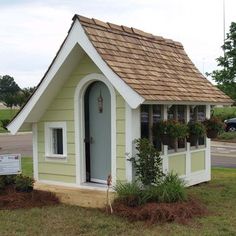 a small white and yellow house with flowers in the window boxes on the front door