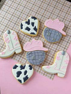 decorated cookies in the shape of cowboy boots and boots on a pink tablecloth background