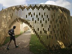 a person walking down a path next to a large wooden structure on the side of a road