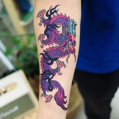 a woman with a tattoo on her arm has a colorful dragon tattooed on it's arm