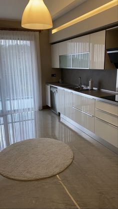 an empty kitchen with white cabinets and beige rug on the floor in front of sliding glass doors