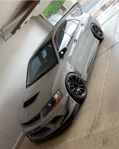 a silver sports car parked in a garage next to a white wall and window sill