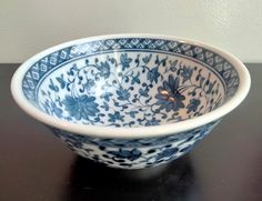 a blue and white bowl sitting on top of a black table next to a wall