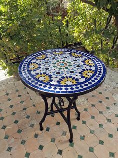 a blue and white table sitting on top of a tiled floor next to a tree