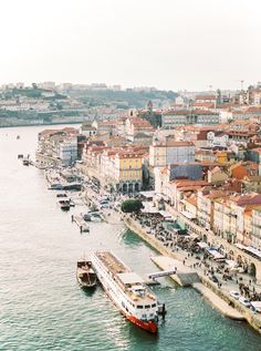 boats are docked in the water next to some buildings and other large buildings on the shore