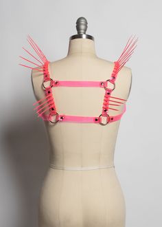 The neon version of the Replicant Chest Harness! Cyberpunk inspired harness made in colorful PVC. Dramatic spikes fan out at the shoulder to create a striking, avant garde, futuristic look. Fit is adjustable with buckle at chest. Silver-toned nickel plated steel hardware. Spikes are plastic zip ties/cable ties and are lightweight and flexible. Available in neon pink (shown) or lime green. Neon pink and neon orange PVC areUV reactive, the lime green PVC is NOT. All spikes colors are UV reactive. Punk Strapped Harness For Cosplay, Punk Style Party Harness With Adjustable Straps, Punk Style Harness With Adjustable Straps For Party, Edgy Party Harness With Straps, Edgy Strapped Party Harness, Edgy Strapped Harness For Parties, Adjustable Punk Harness For Parties, Edgy Adjustable Party Harness, Edgy Adjustable Harness For Parties