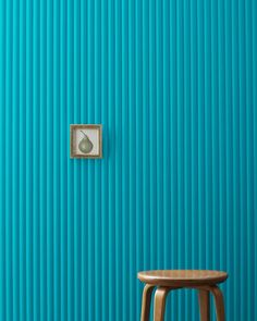 a wooden stool sitting in front of a blue wall