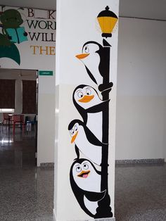 an image of three penguins on the side of a pole with a lamp post in the background