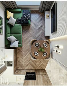 an overhead view of a living room and dining area with wood flooring, green couches, coffee table and pictures on the wall