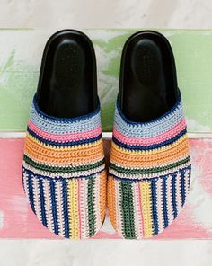 a pair of colorful slippers sitting on top of a pink and green striped mat