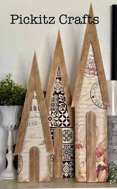 three wooden houses sitting on top of a table next to a vase with flowers in it