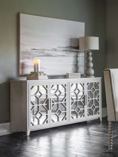 a white sideboard in a room with a painting on the wall