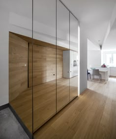 an empty room with wooden flooring and glass doors on the wall, next to a dining table