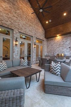 an outdoor living room with couches and tables in front of brick walls, lighting up the ceiling