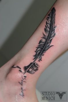 a black and white feather tattoo on the ankle with words written below it in cursive writing