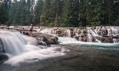 two people are standing at the edge of a waterfall