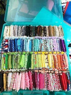 an open plastic container filled with lots of different colored bracelets and necklaces on display