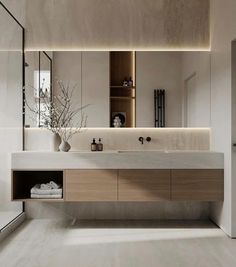 a bathroom with a large mirror above the sink and cabinets in front of it that have lights on them