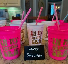 pink cups with straws in them sitting on a counter next to a sign that says never smoothie