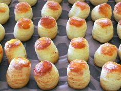 rolls covered in orange sauce sitting on top of a baking sheet next to each other