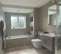 a bathroom with a toilet, sink and bathtub next to a window in the wall