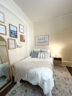 a bed sitting in a bedroom next to a wall with pictures on it and a mirror