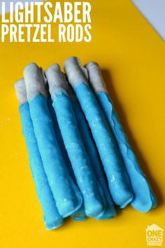 four blue and white marshmallows sitting on top of a yellow table with the words lightsaber pretzel rods