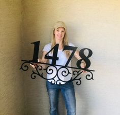 a woman standing behind a metal clock with numbers on it