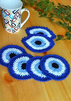 three crocheted coasters on a wooden table with a coffee cup and plant