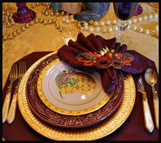 a table set with gold and purple place settings