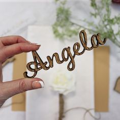 a person holding up the word argela in front of some paper and flowers