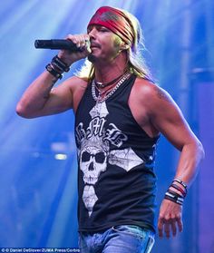 a man with long hair wearing a bandana and holding a microphone in his hand