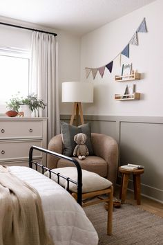 a bed room with a neatly made bed and a teddy bear sitting on the chair