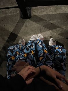 two people in pajamas are holding hands over each other's feet on the ground