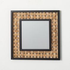 a mirror mounted to the side of a wall with a wooden frame and black trim