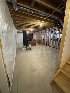 an empty room with wooden floors and white sheets on the walls, next to some stairs